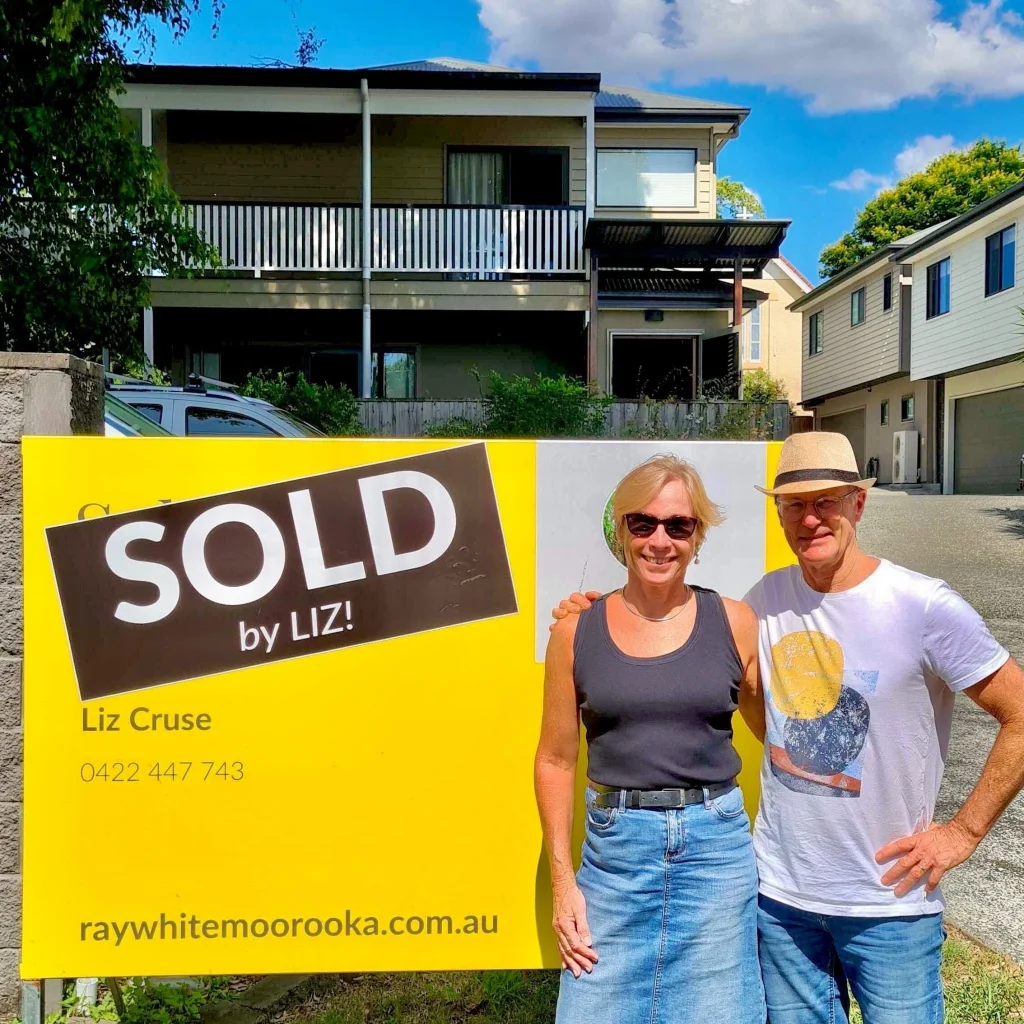 Sold Brisbane house with homeowners celebrating beside a sold property sign