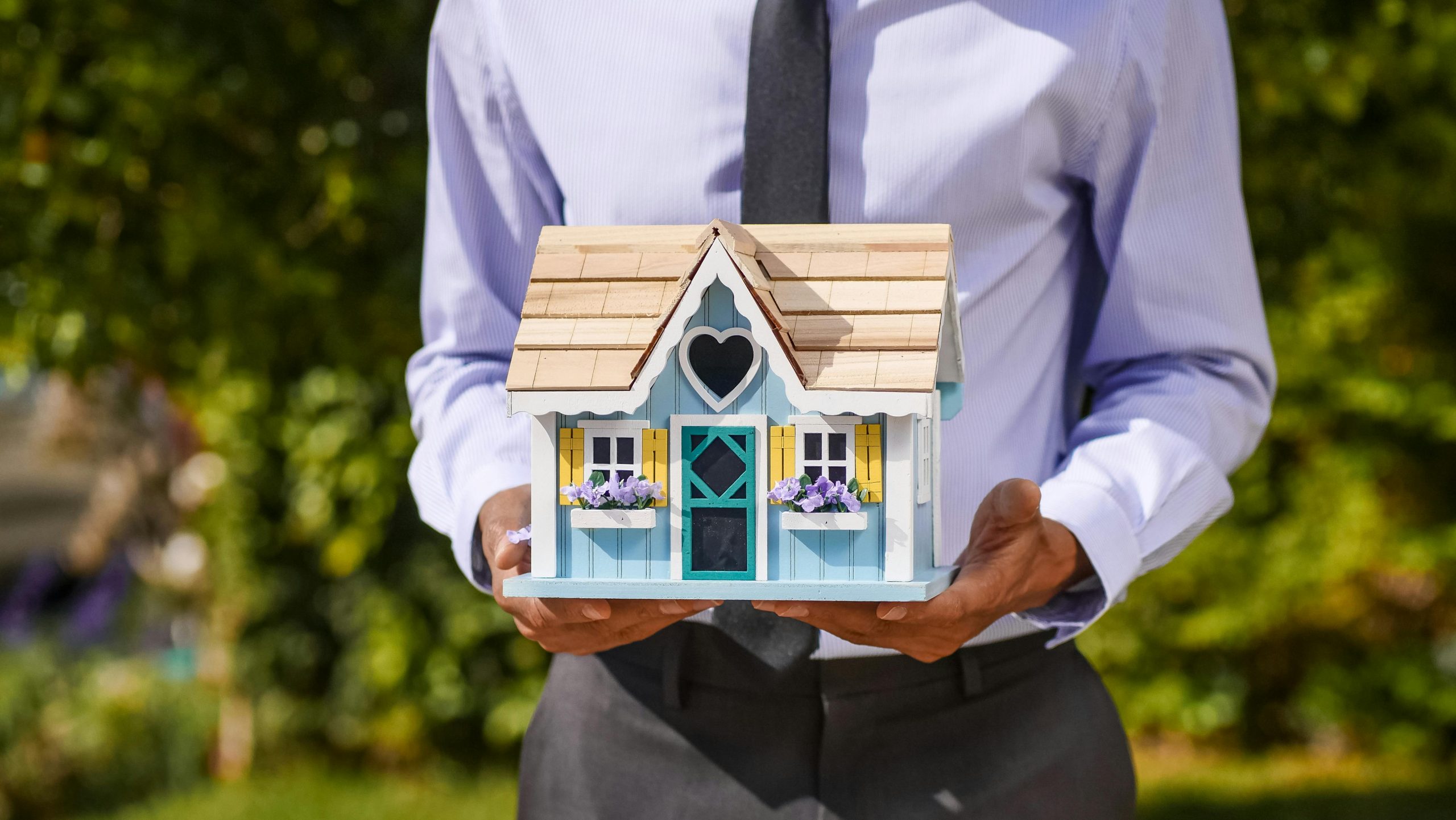Real estate professional holding a small model house, representing home downsizing in Brisbane and property planning support