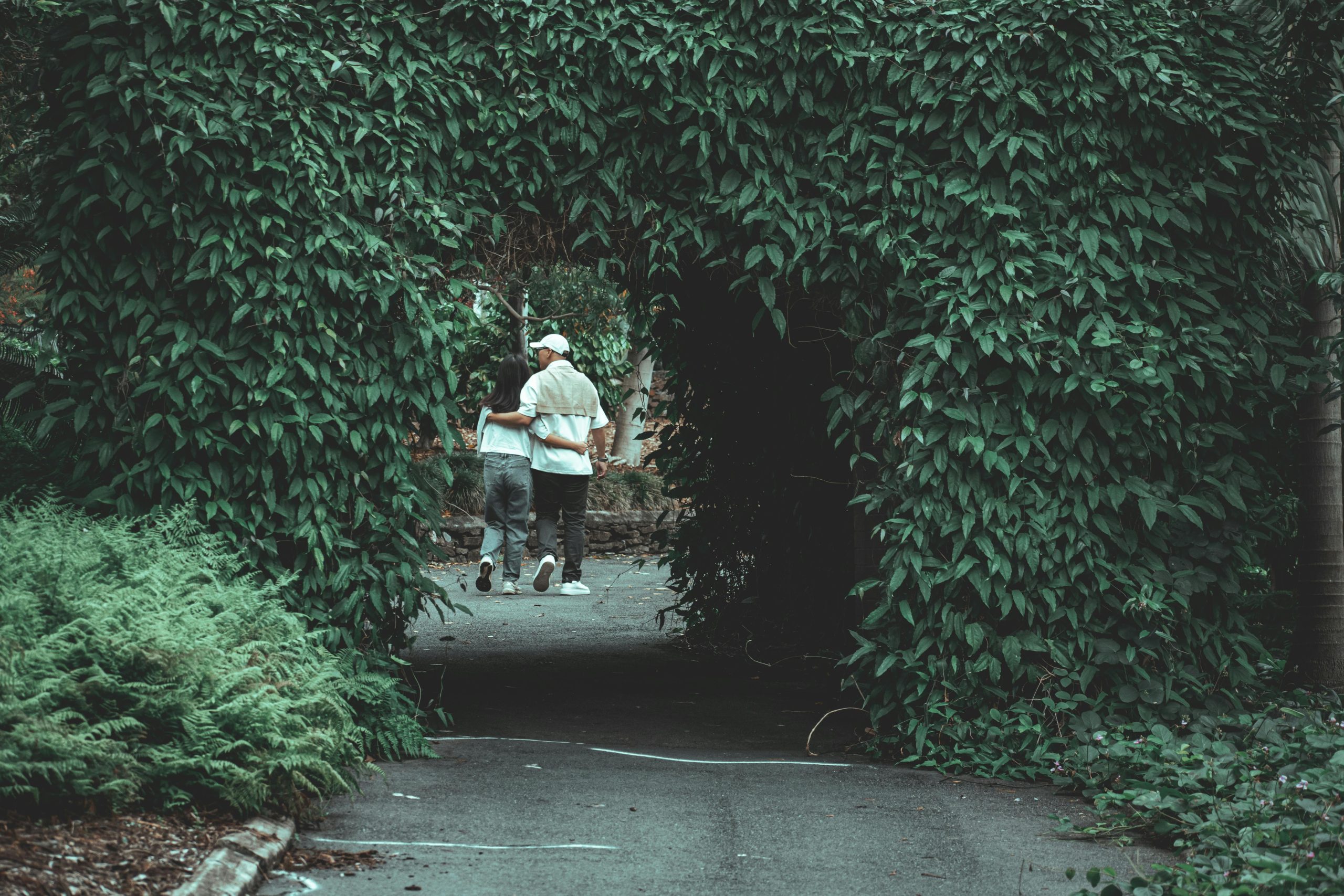 Couple walking through a leafy archway at Mount Coot-tha Reserve, Brisbane