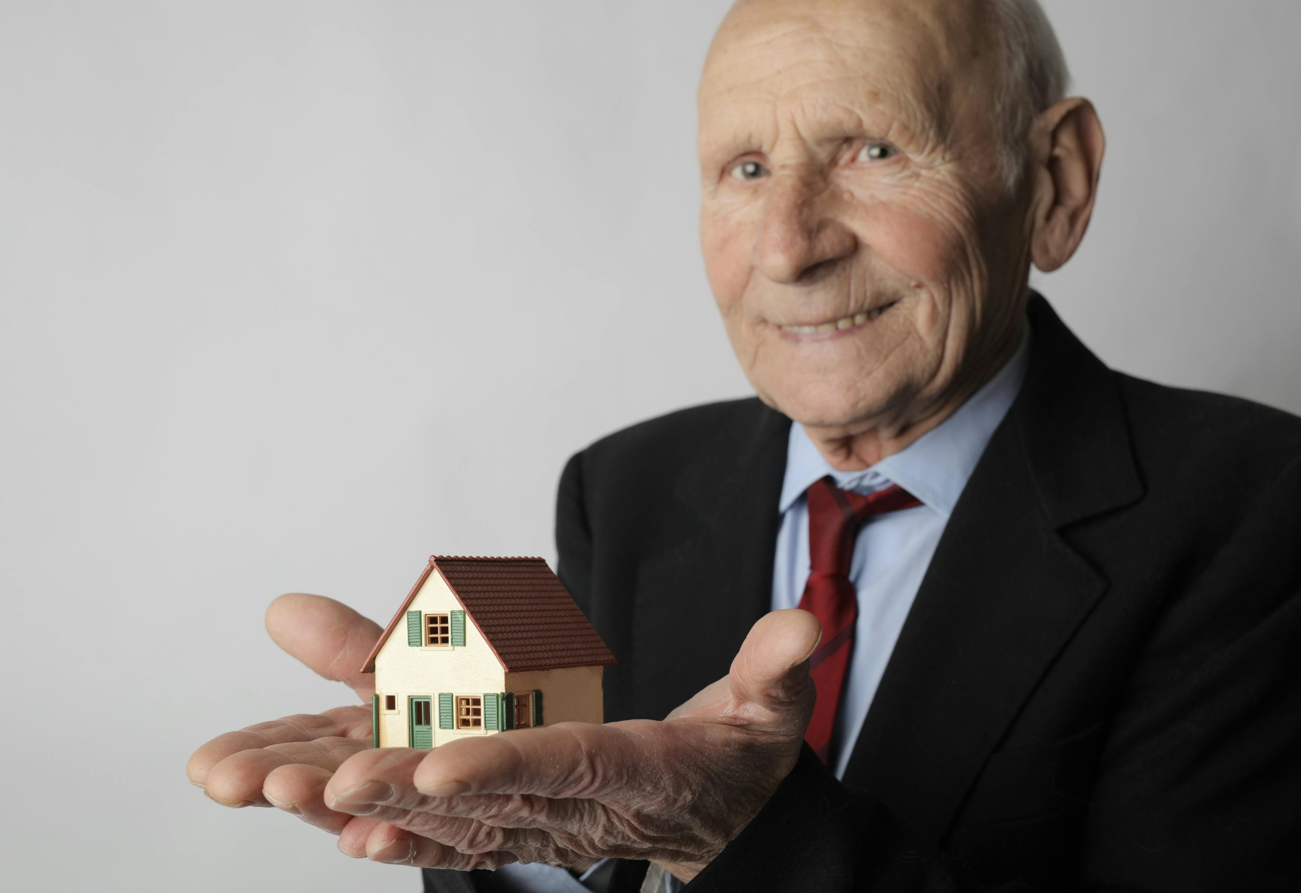 Retiree holding a small model house, representing retirement downsizing in Brisbane and property planning support