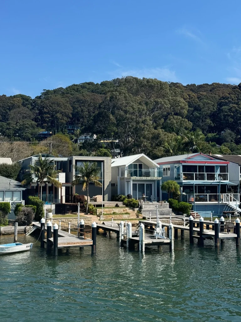 Waterfront Brisbane homes with docks and boats along a scenic coastal shoreline.