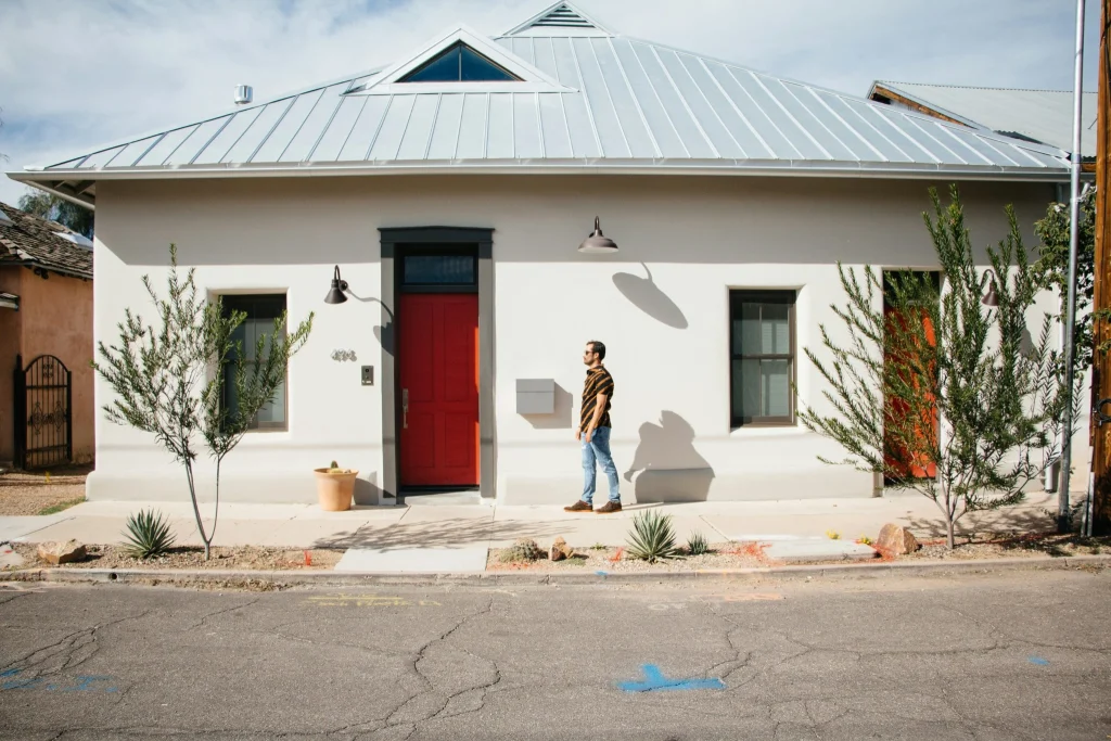 Man outside a modern white house with red doors in Brisbane.